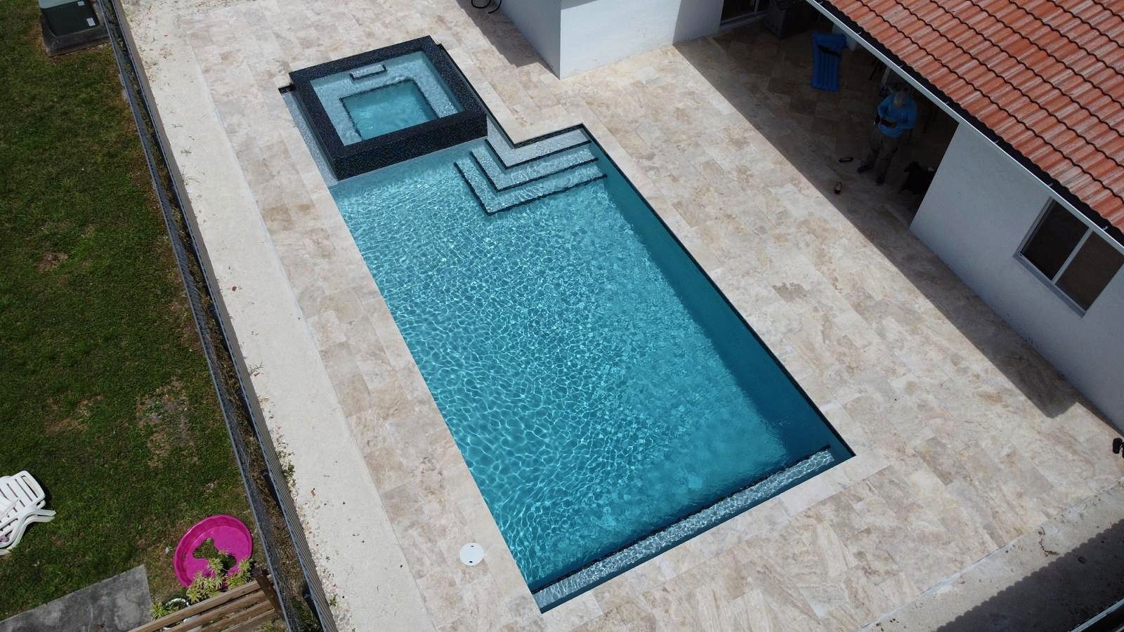 An aerial view of a large swimming pool in front of a house.