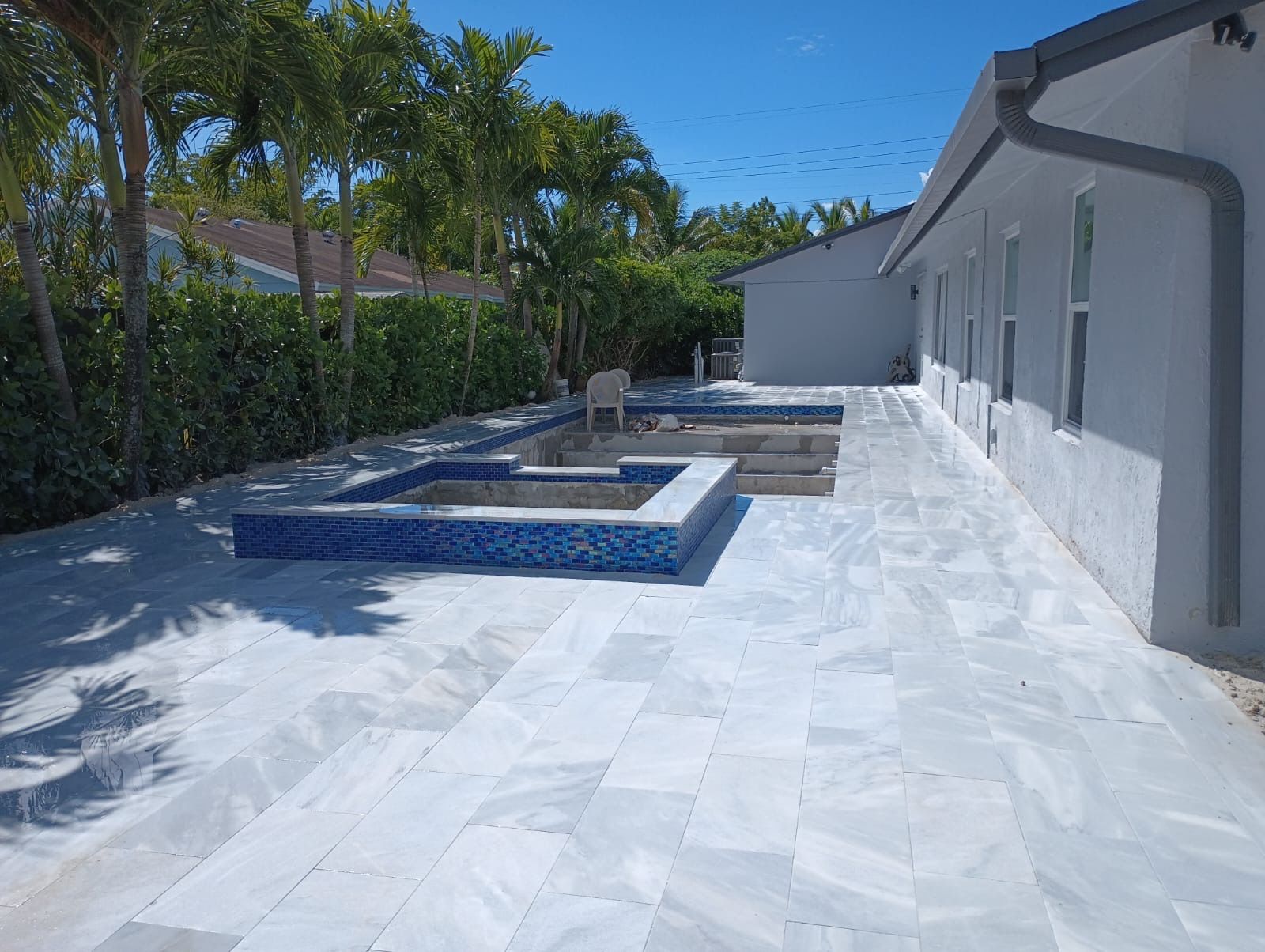 A large patio with a pool in the backyard of a house.