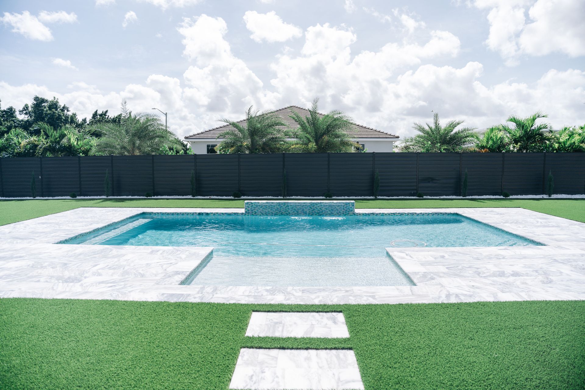 There is a large swimming pool in the backyard of a house.