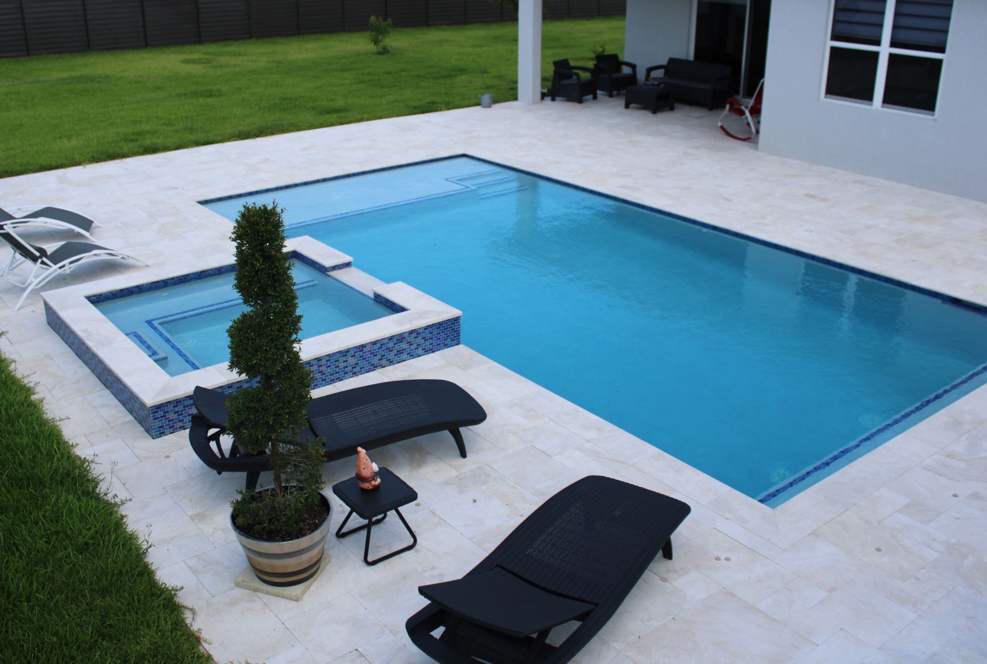 A large swimming pool with a hot tub in the backyard