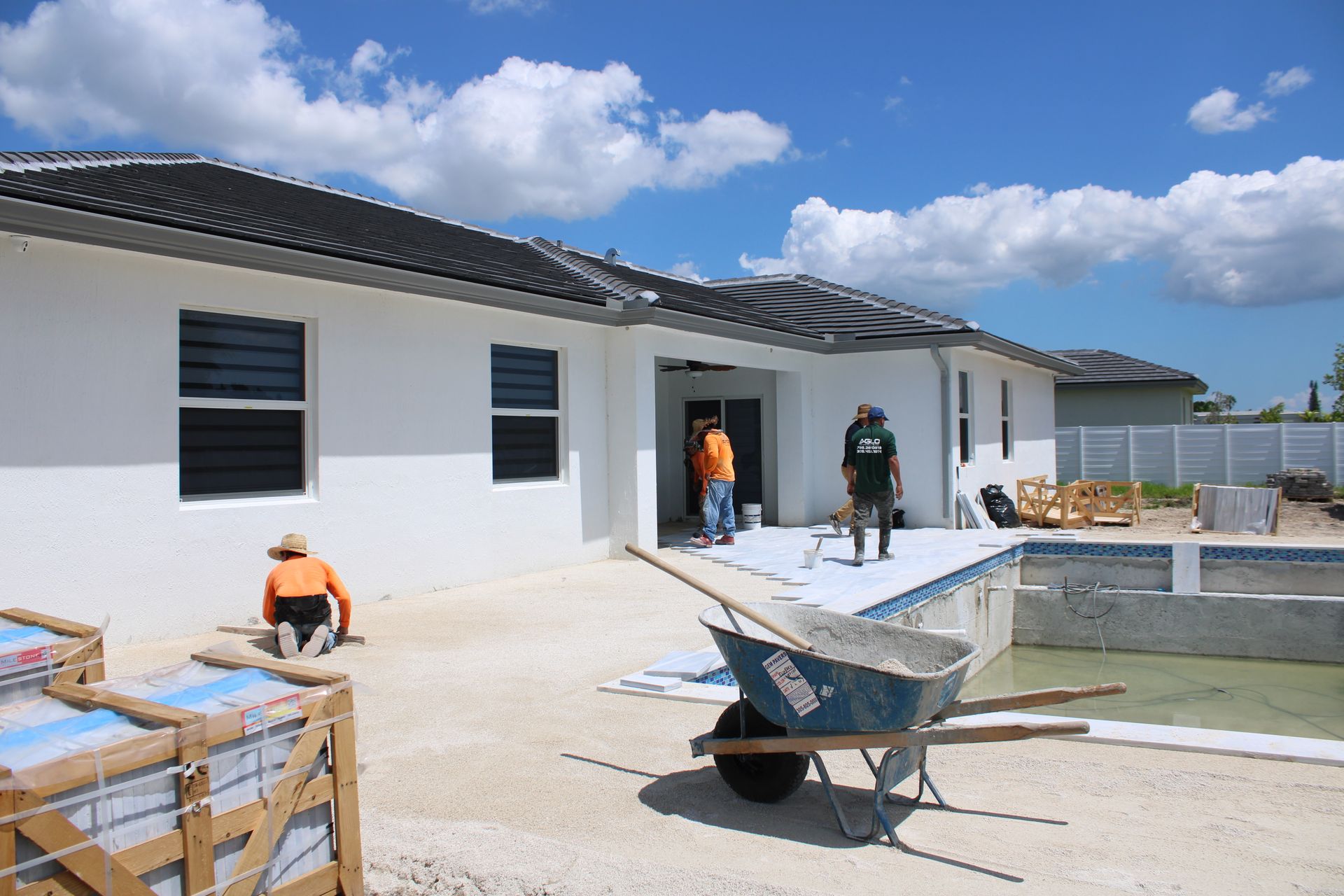 A wheelbarrow is parked in front of a house under construction.