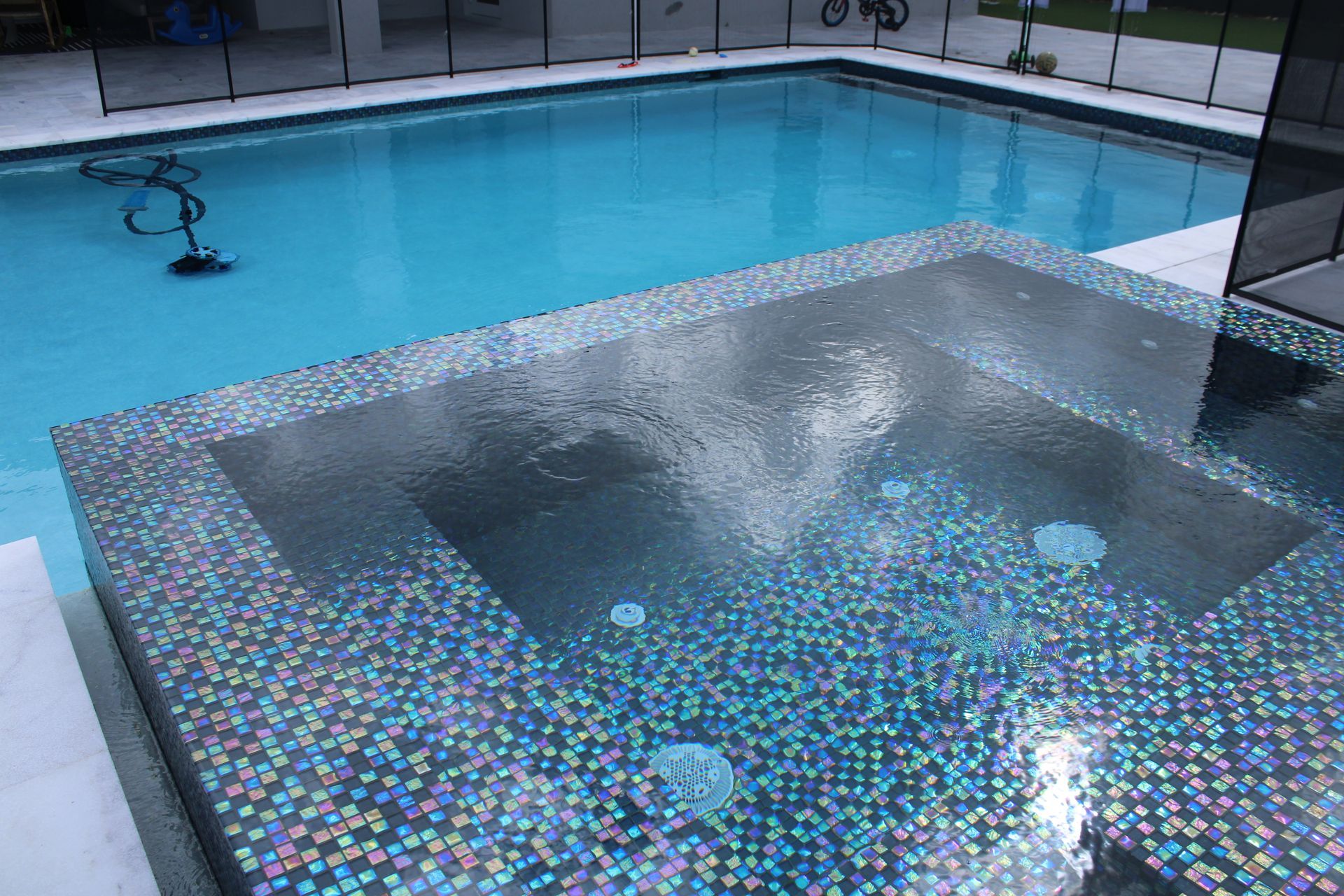 A swimming pool with a hot tub in the middle of it.