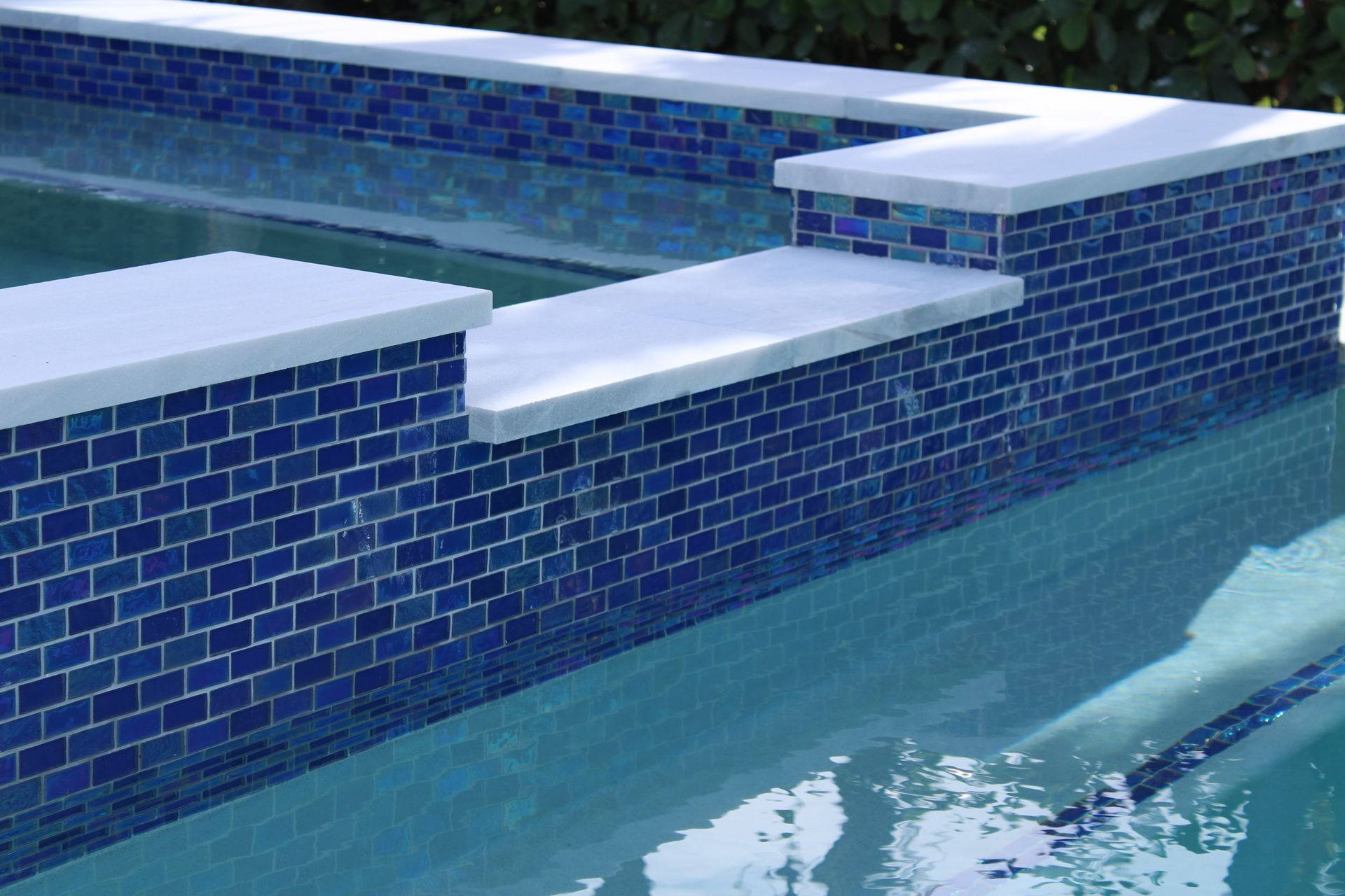 A swimming pool with blue tiles and white steps