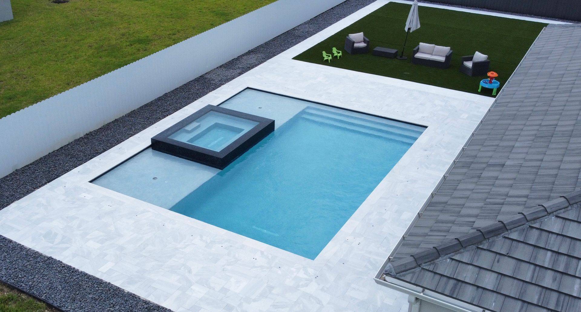 An aerial view of a swimming pool with a hot tub in the middle.