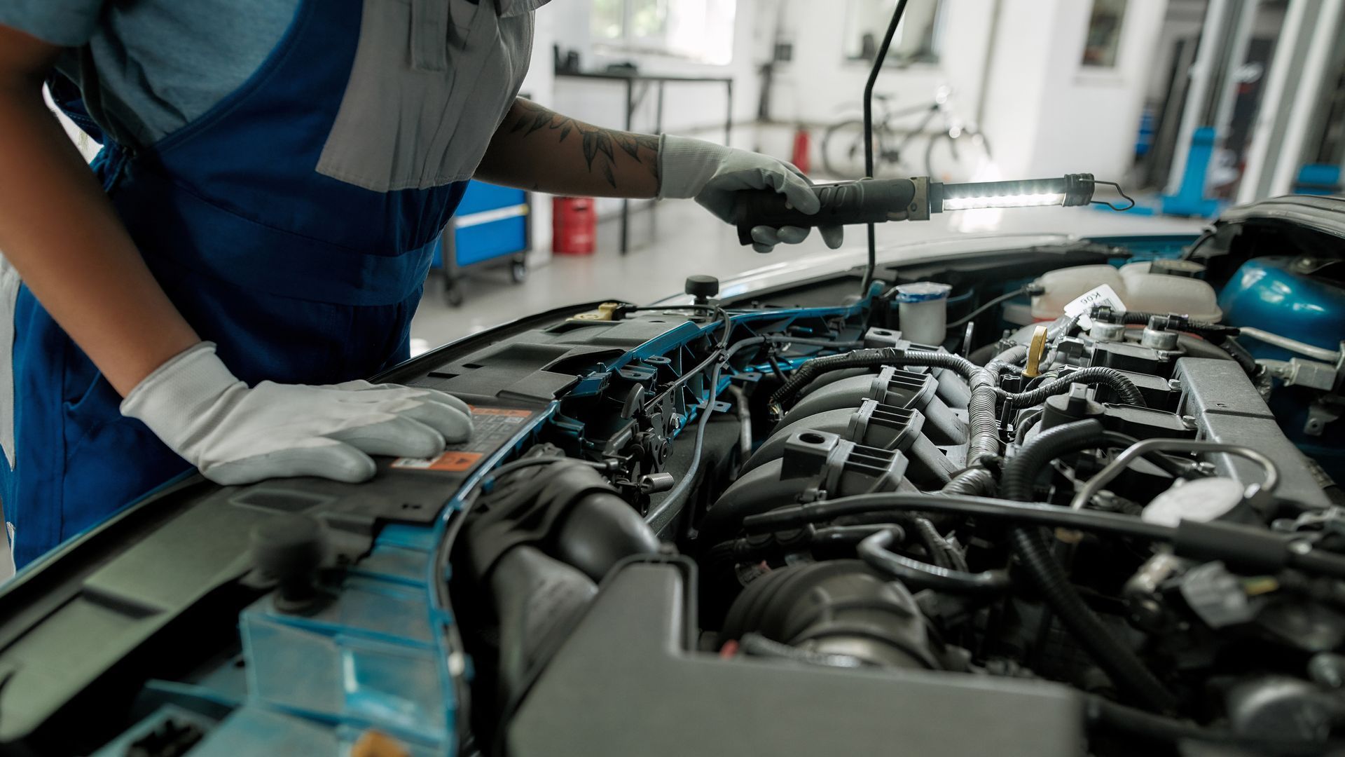 Close-up of a car’s engines and motor as a car mechanic checks it with a light, the car’s hood up. Close-up of a car’s engines and motor as a car mechanic checks it with a light, the car’s hood up.