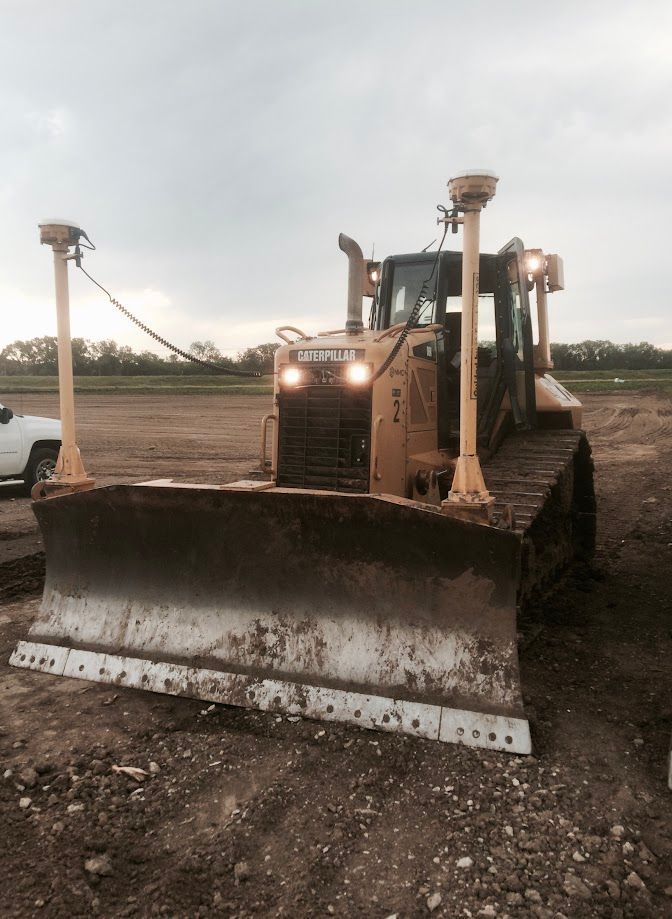 Yellow Caterpillar bulldozer on dirt, with GPS towers.