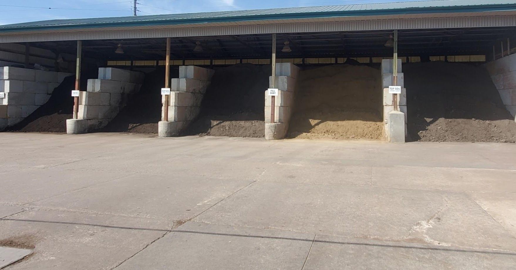 Covered storage bins filled with varying colored materials; concrete structure outdoors.