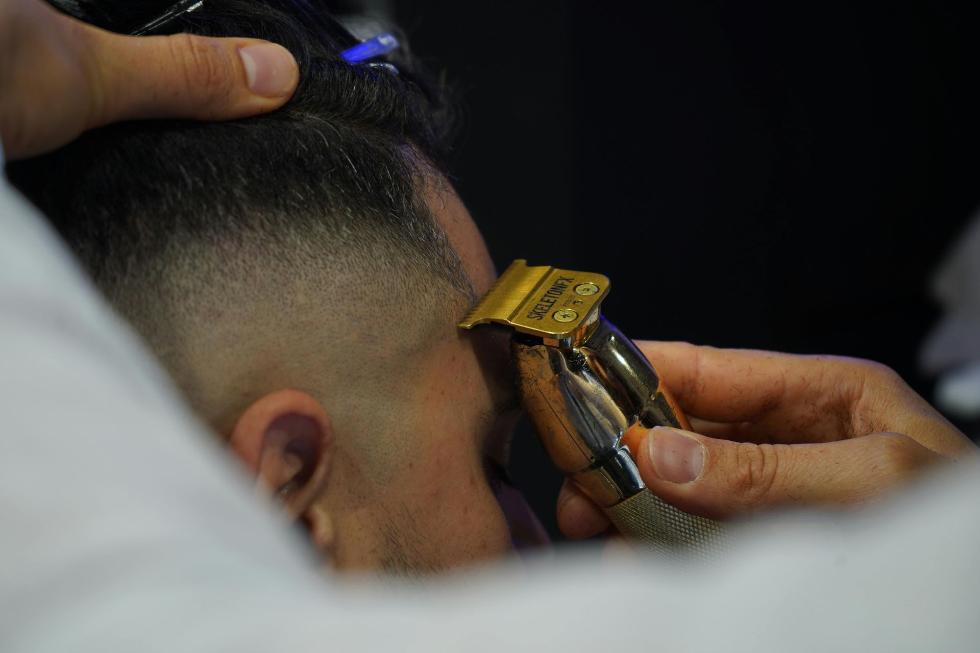 Barber trimming hair with clippers, close-up at the legendary right touch barbershop in colorado spings, co.