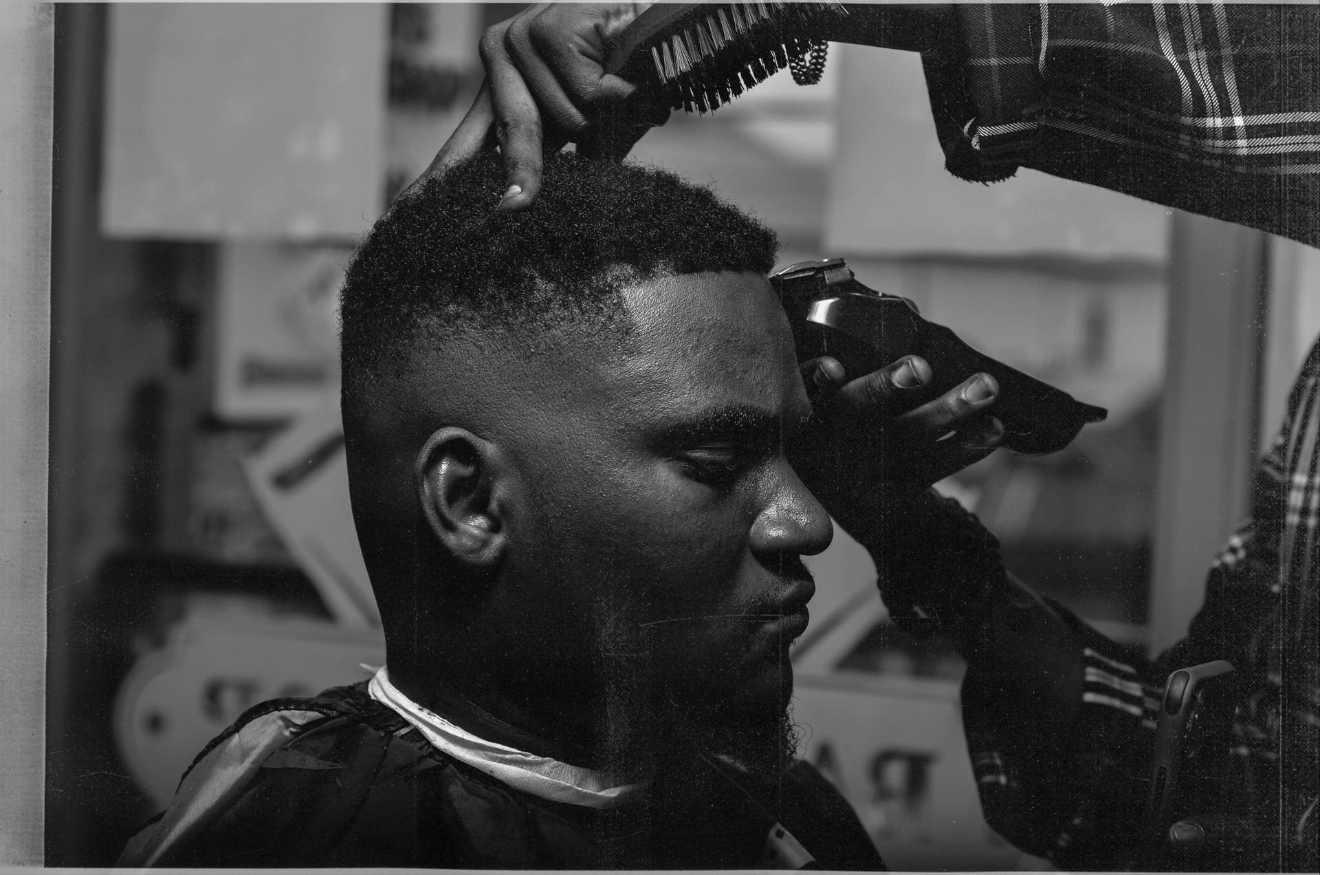 Barber cutting hair with clippers. Man in barber chair, hair being trimmed.