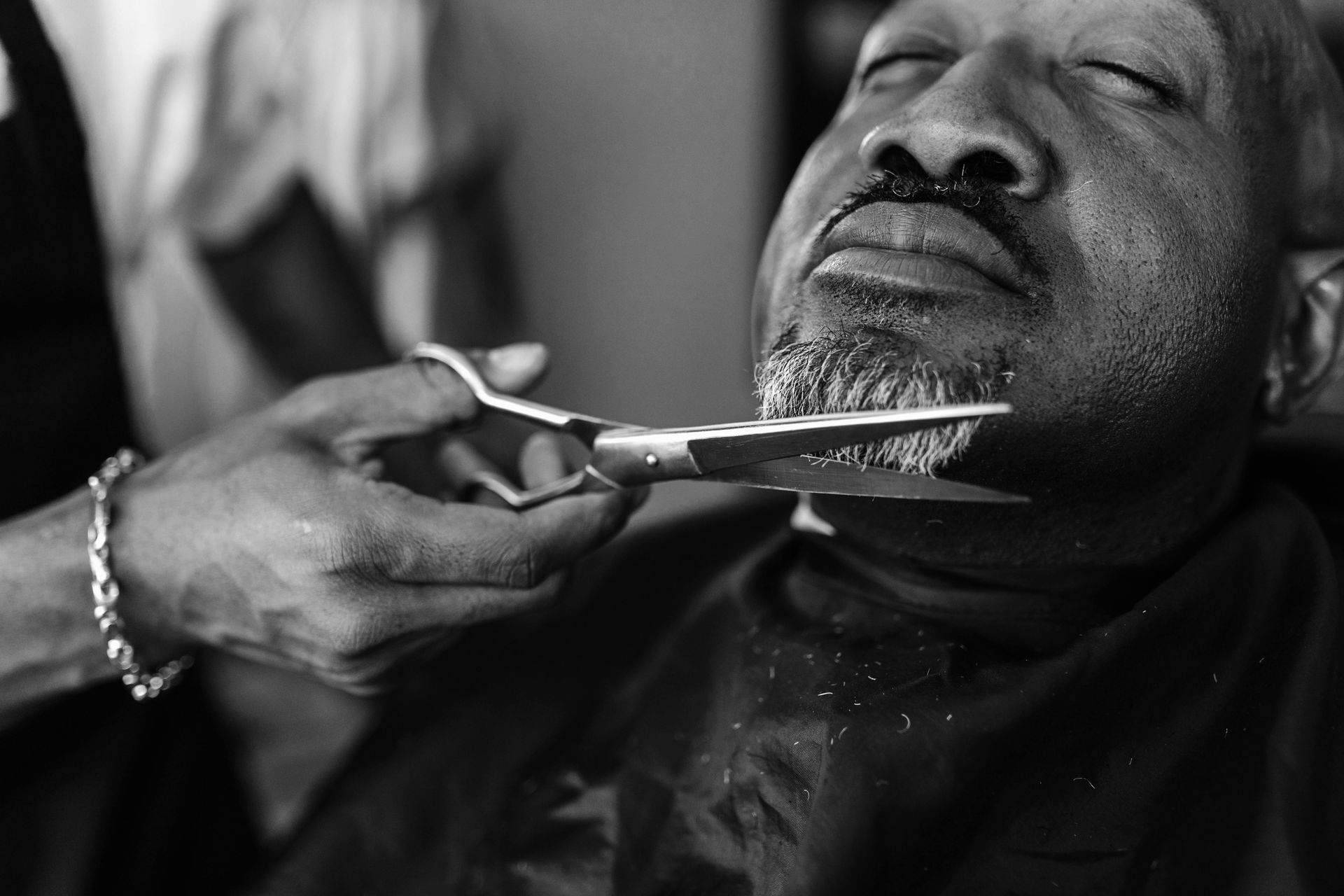 Man getting beard trimmed with scissors.