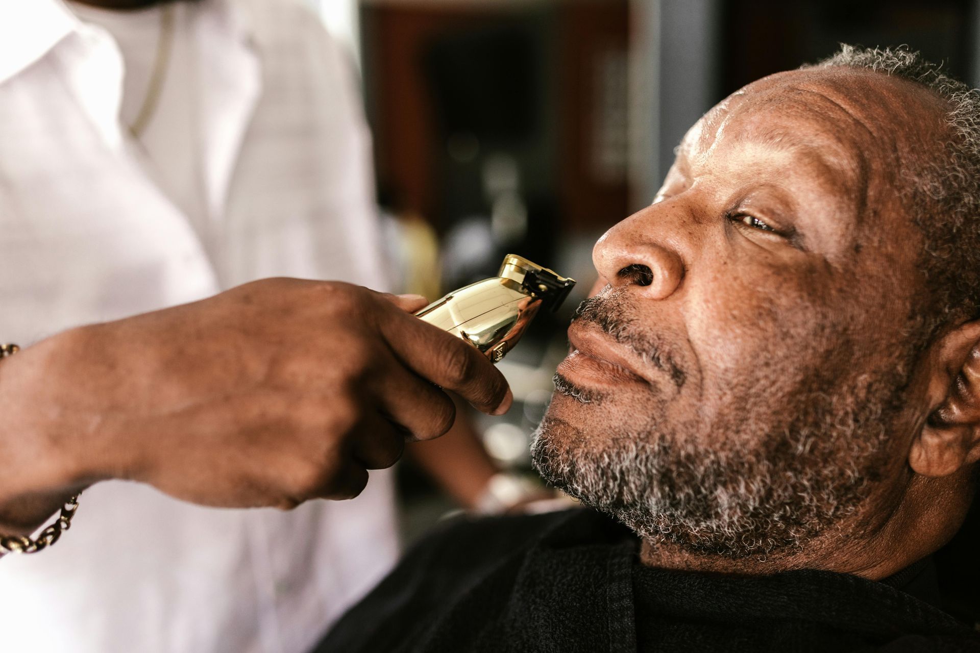 Barber trimming a person's beard with clippers at the lengendary right touch barbershop in Colorado Springs, CO.