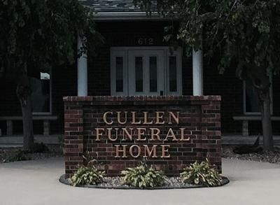 Cullen Funeral Home sign in brick, with building and columns behind it.