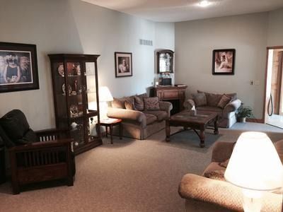Living room with sofas, armchair, display cabinet, and framed artwork.