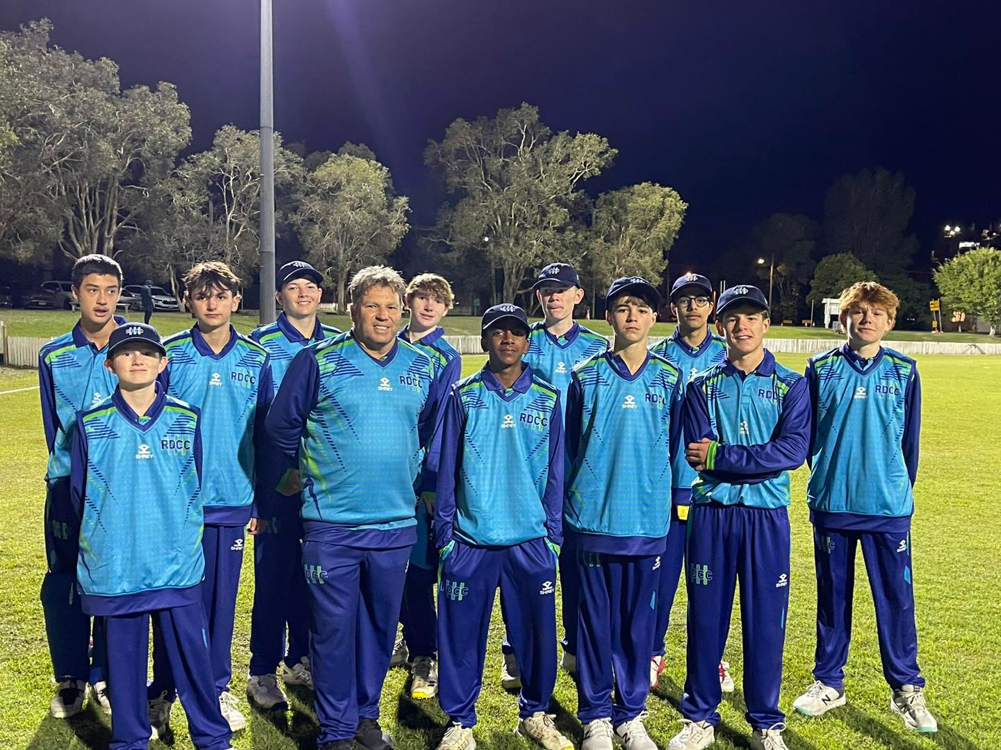 A cricket player with the number 25 on his back is standing on the field.