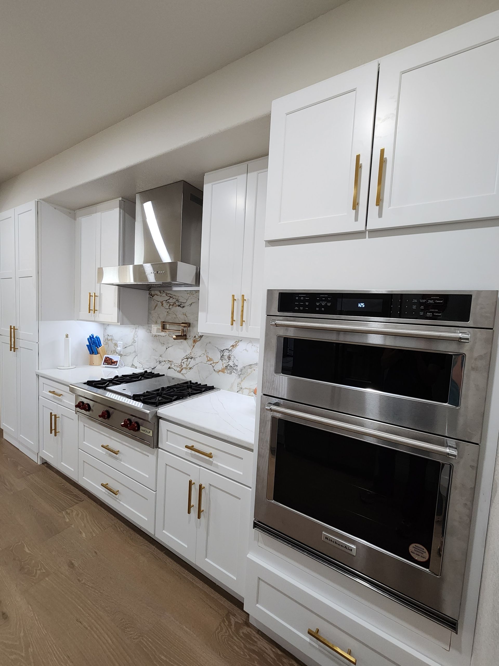 White kitchen with stainless steel appliances and gold hardware.