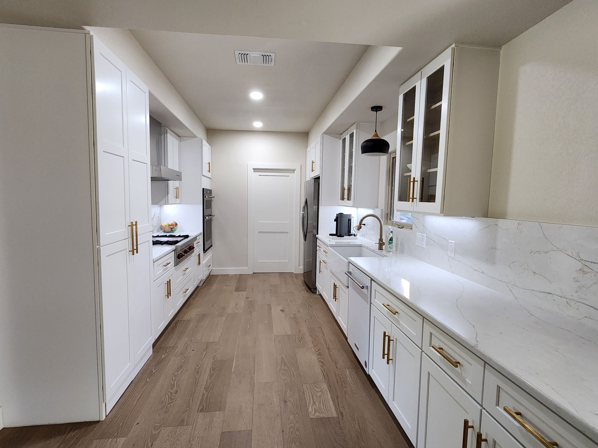 White kitchen with gold hardware and light wood floor.