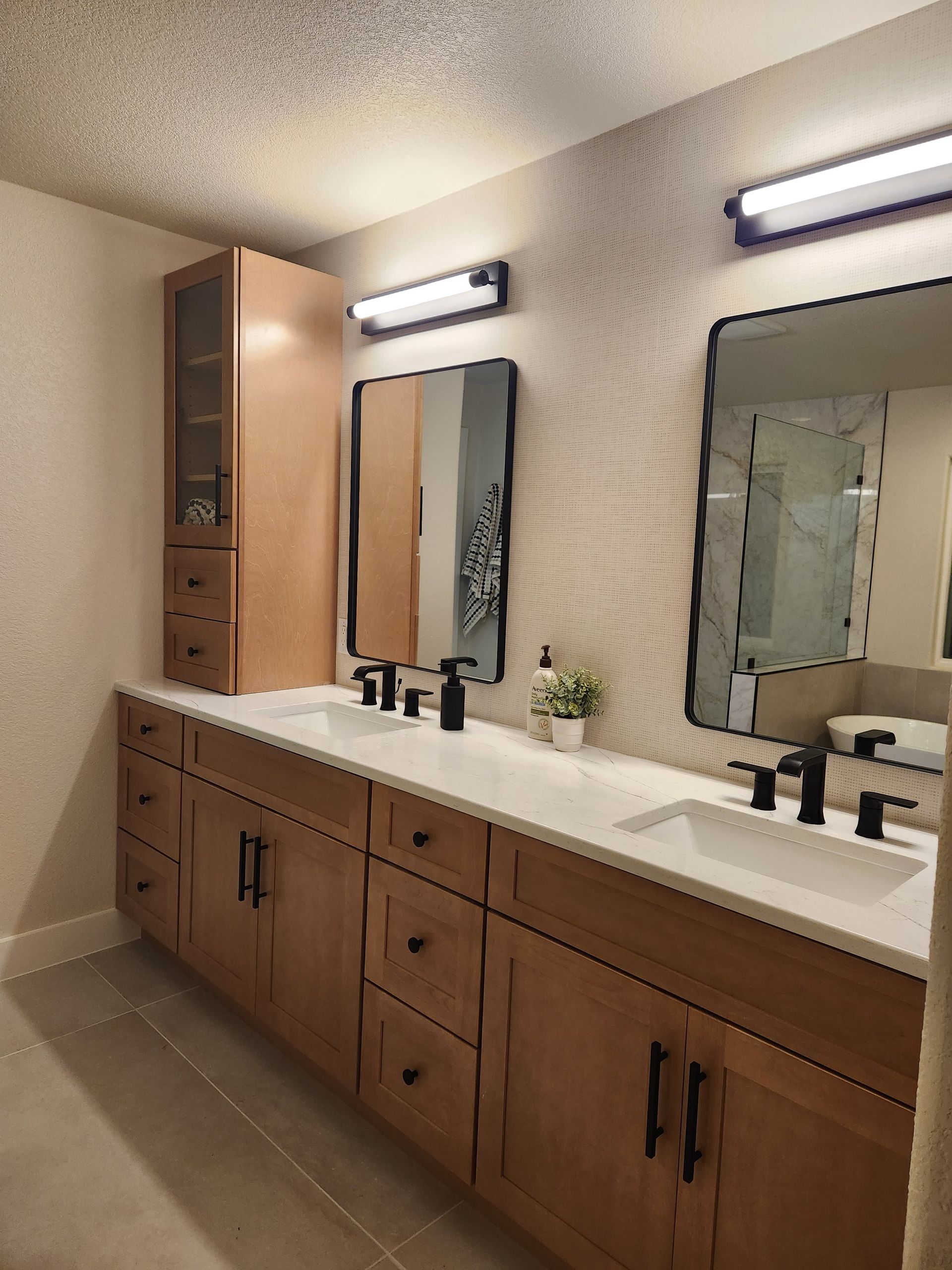 Modern bathroom with dual sinks, brown cabinets, black fixtures, and light-colored walls.