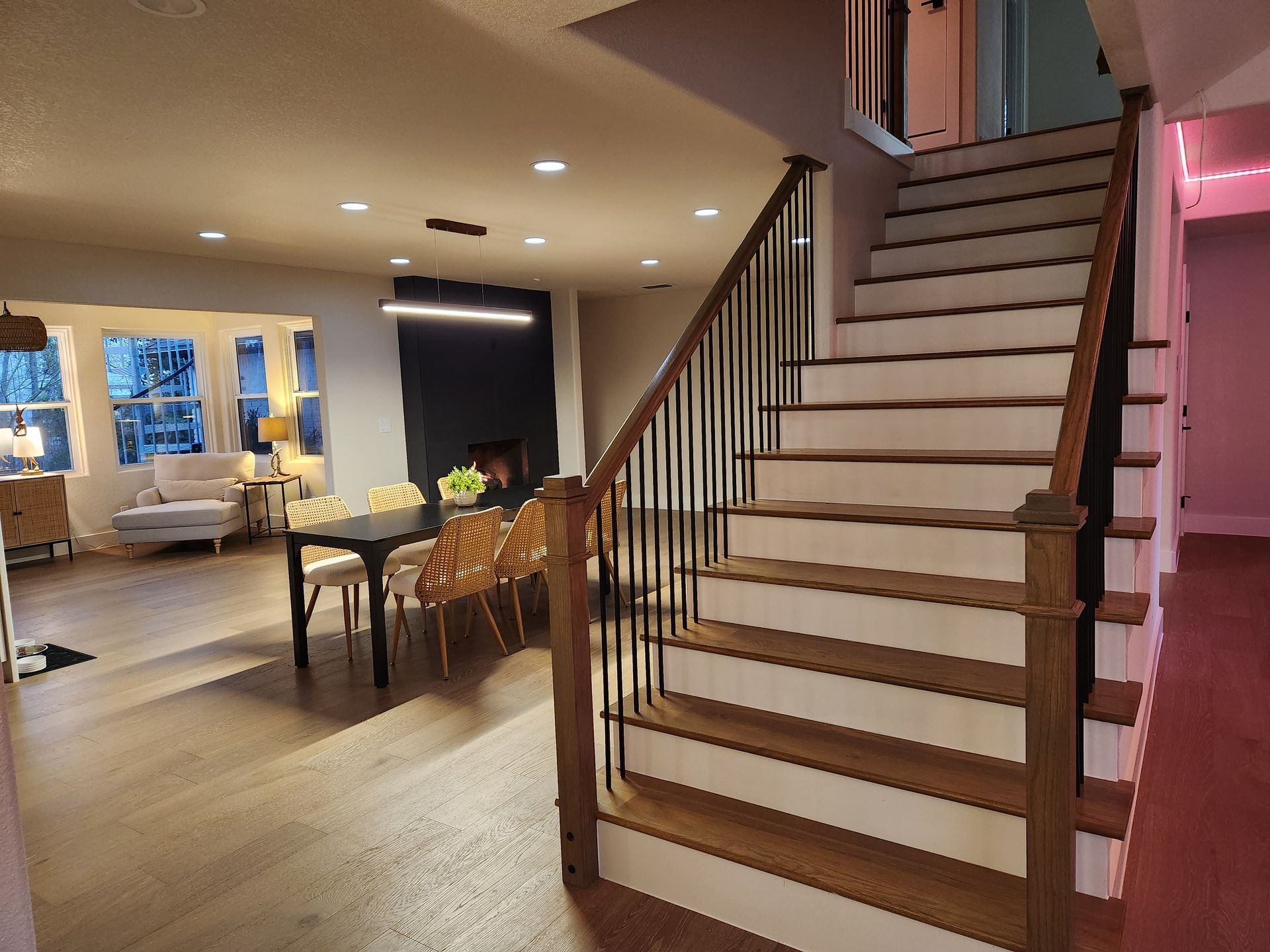 Wooden staircase leading to a dining area with a long table and open living space.