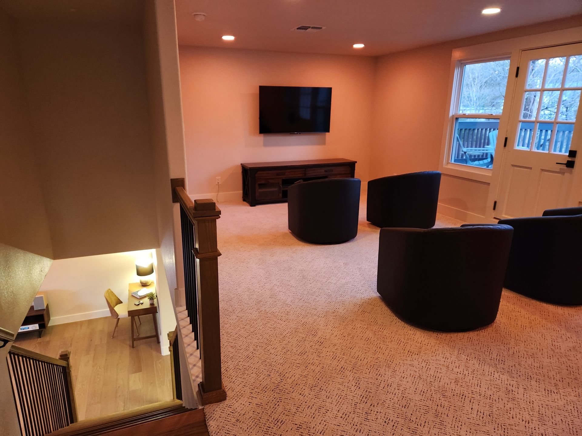 Interior view: basement entertainment area with chairs, TV, and wooden accents.