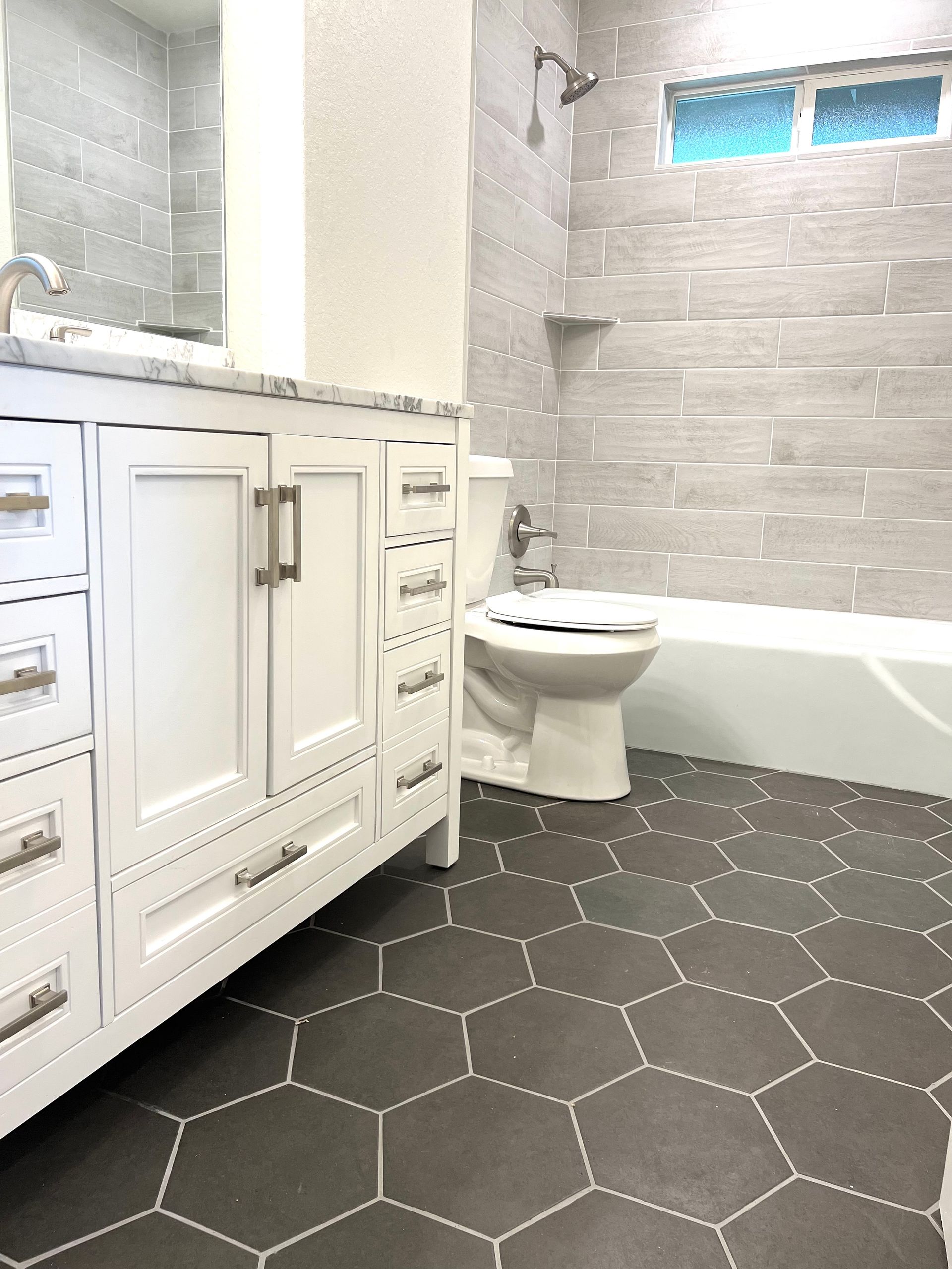 Bathroom with white vanity, gray hex tiles, and gray tiled walls.
