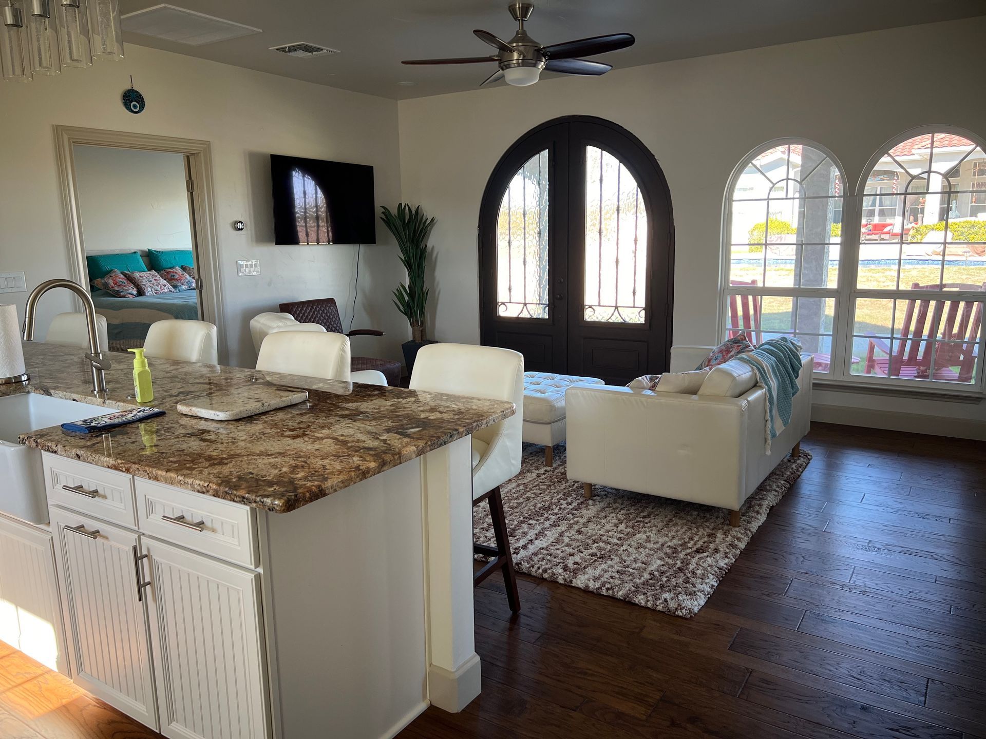 Bright living space with kitchen island, couch, dark arched doorway, and windows.