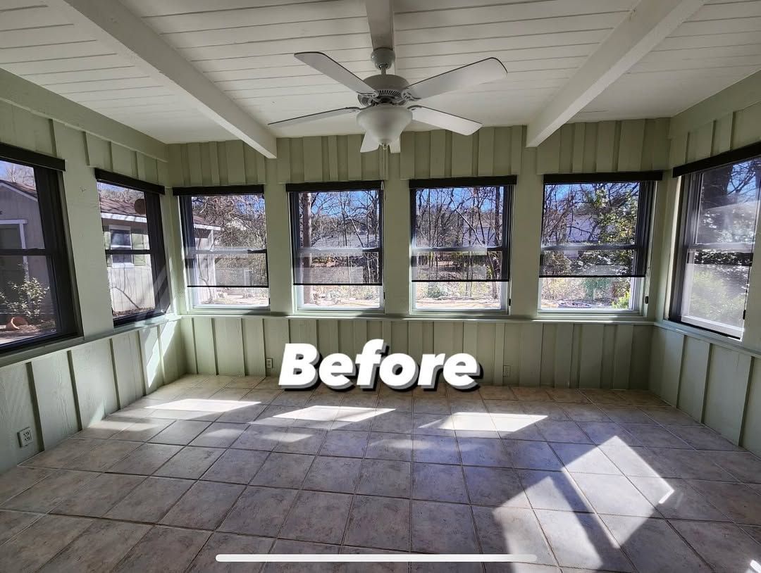 Before image of sunroom with green paneling, white ceiling beams, and a ceiling fan. Large windows.