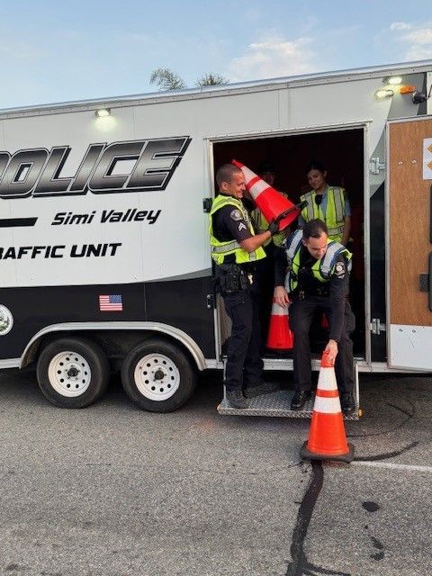 Police officers placing traffic cones near a trailer marked
