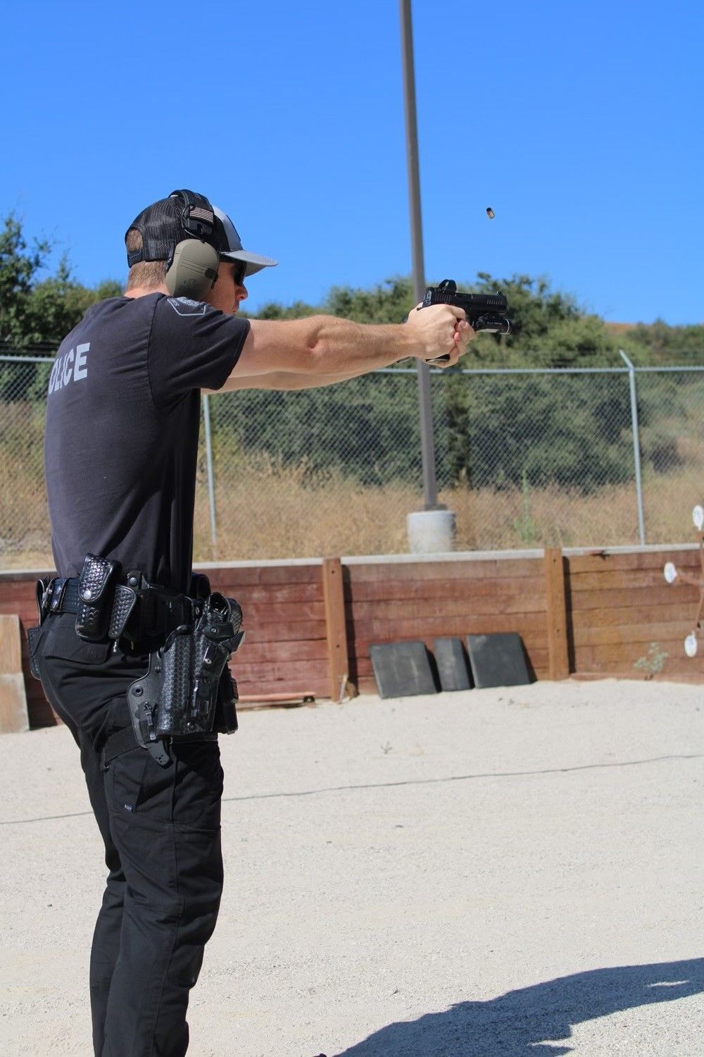 Man in black shirt and pants shoots handgun at a range.