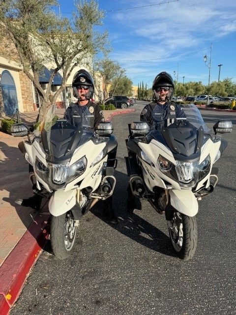 Two motorcycle officers on white motorcycles, outdoors. Sunny day.