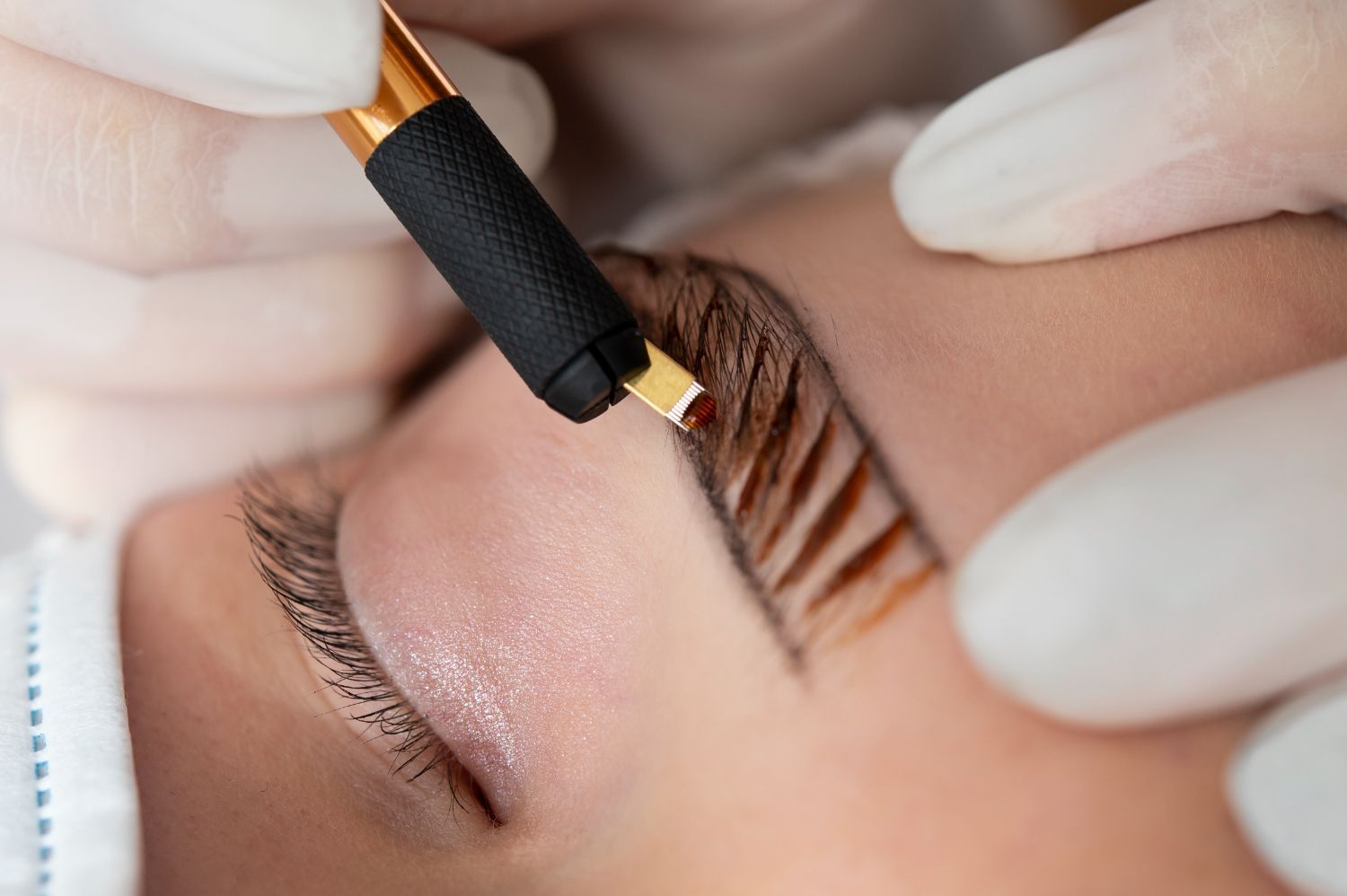 A woman is getting a permanent makeup tattoo on her eyebrows.