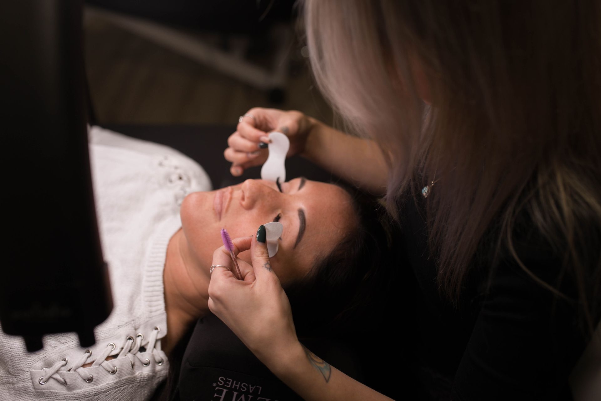 A woman is getting her eyelashes done at a beauty salon.