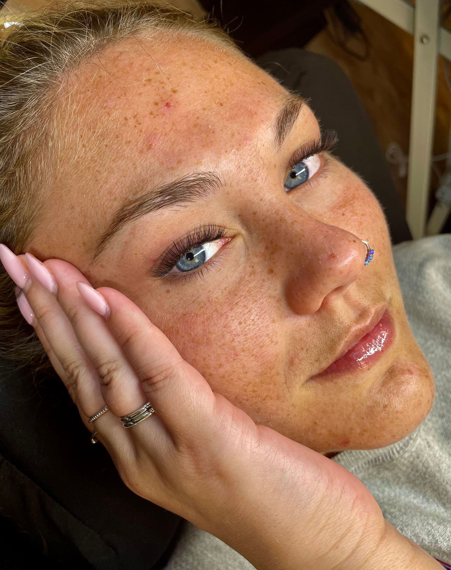 A close up of a woman 's face with her hand on her face.