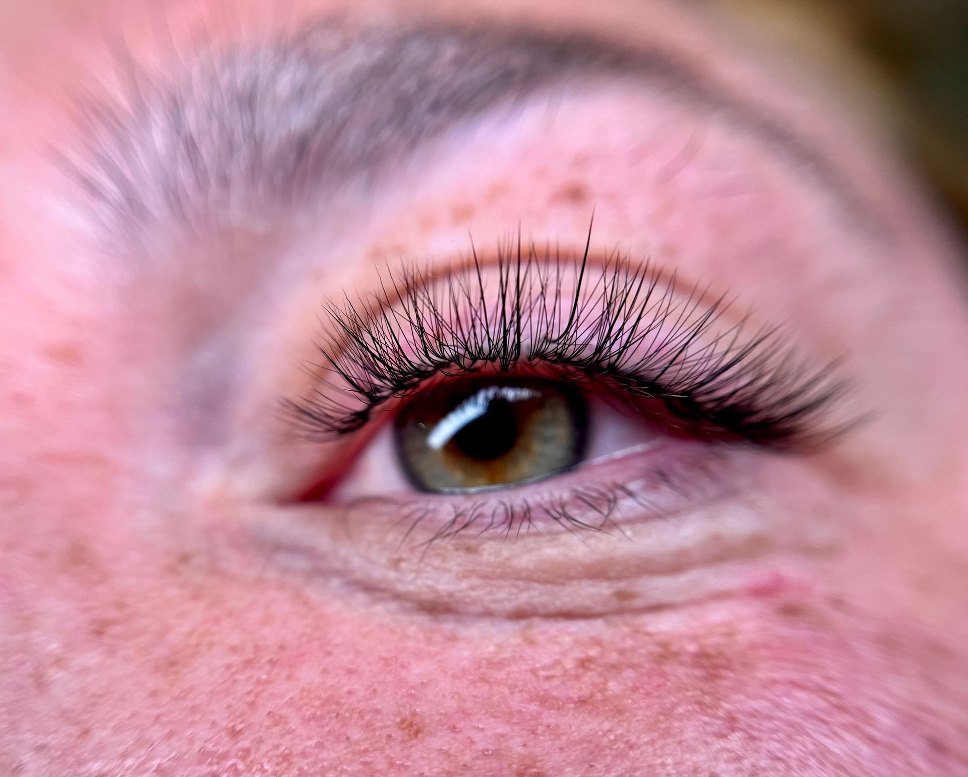 A close up of a woman 's eye with long eyelashes and freckles.