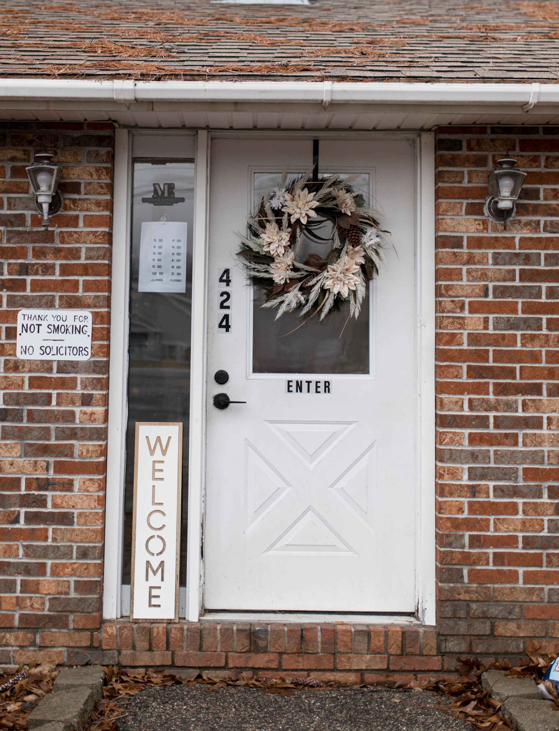 A white door with a wreath hanging on it and a welcome sign.