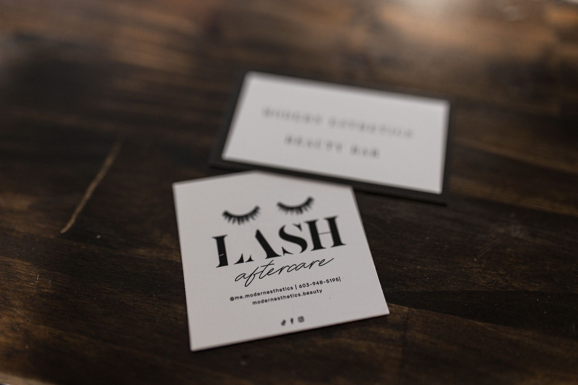 Two business cards for lash on a wooden table