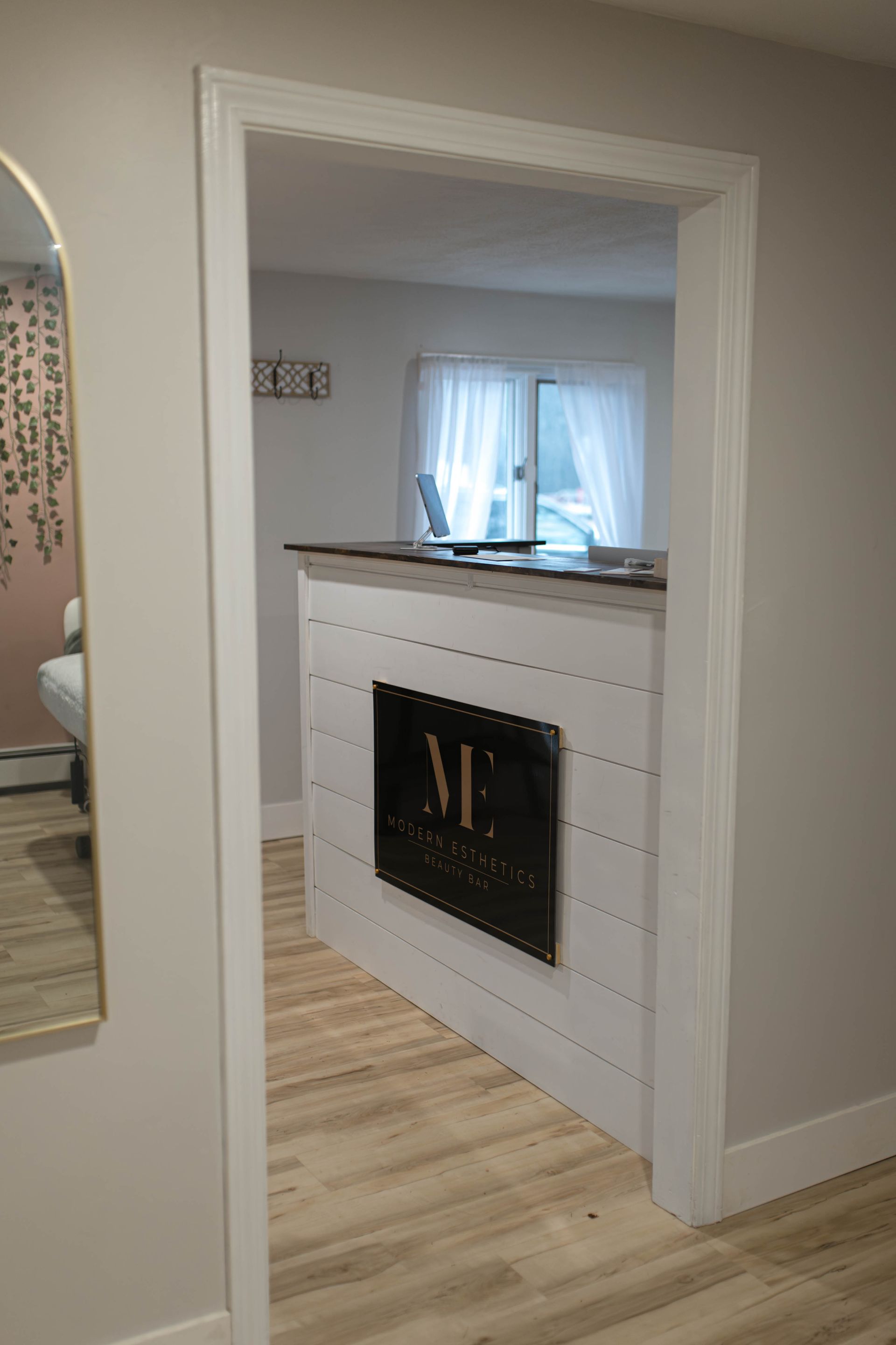 A hallway with a reception desk and a mirror.