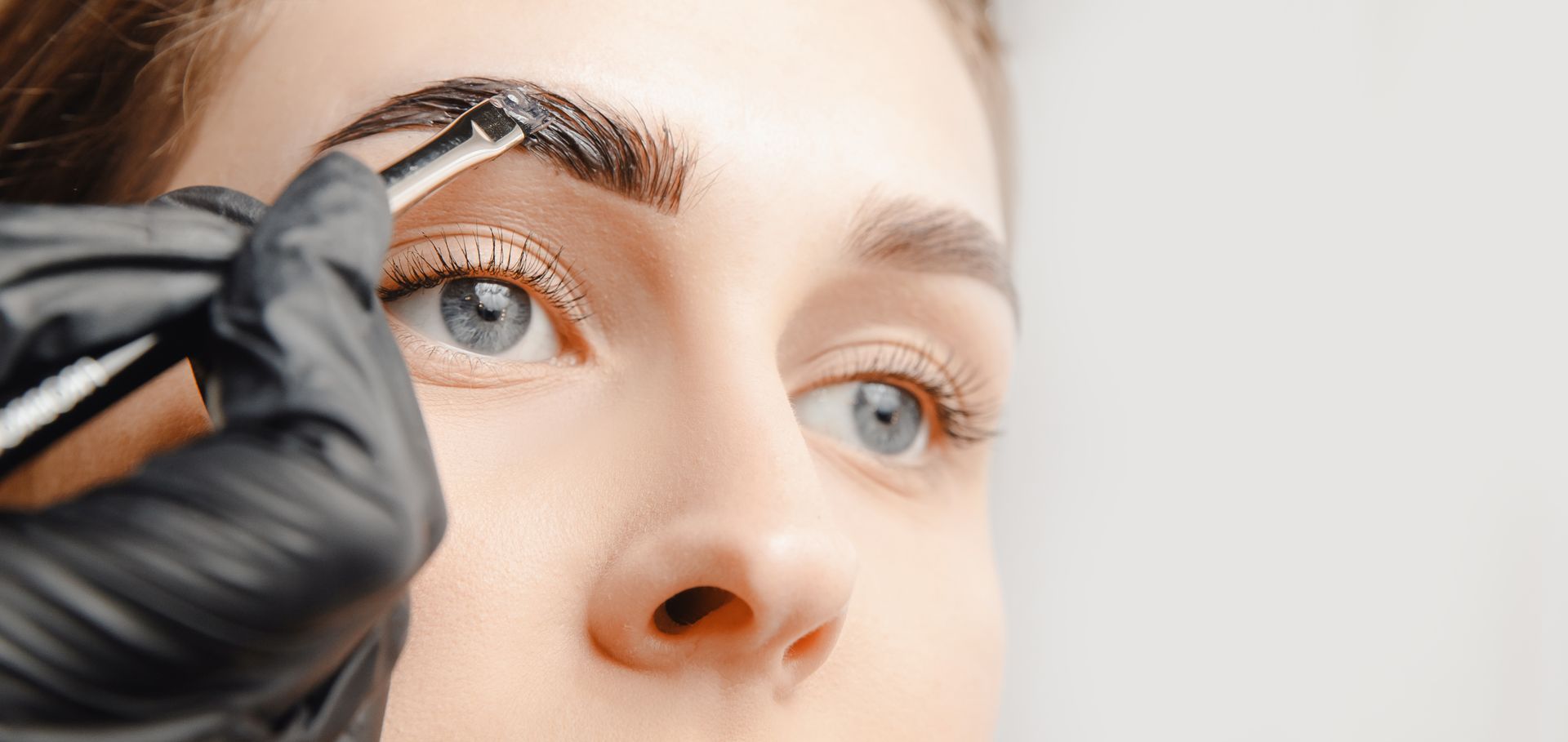 A woman is getting her eyebrows dyed in a salon.