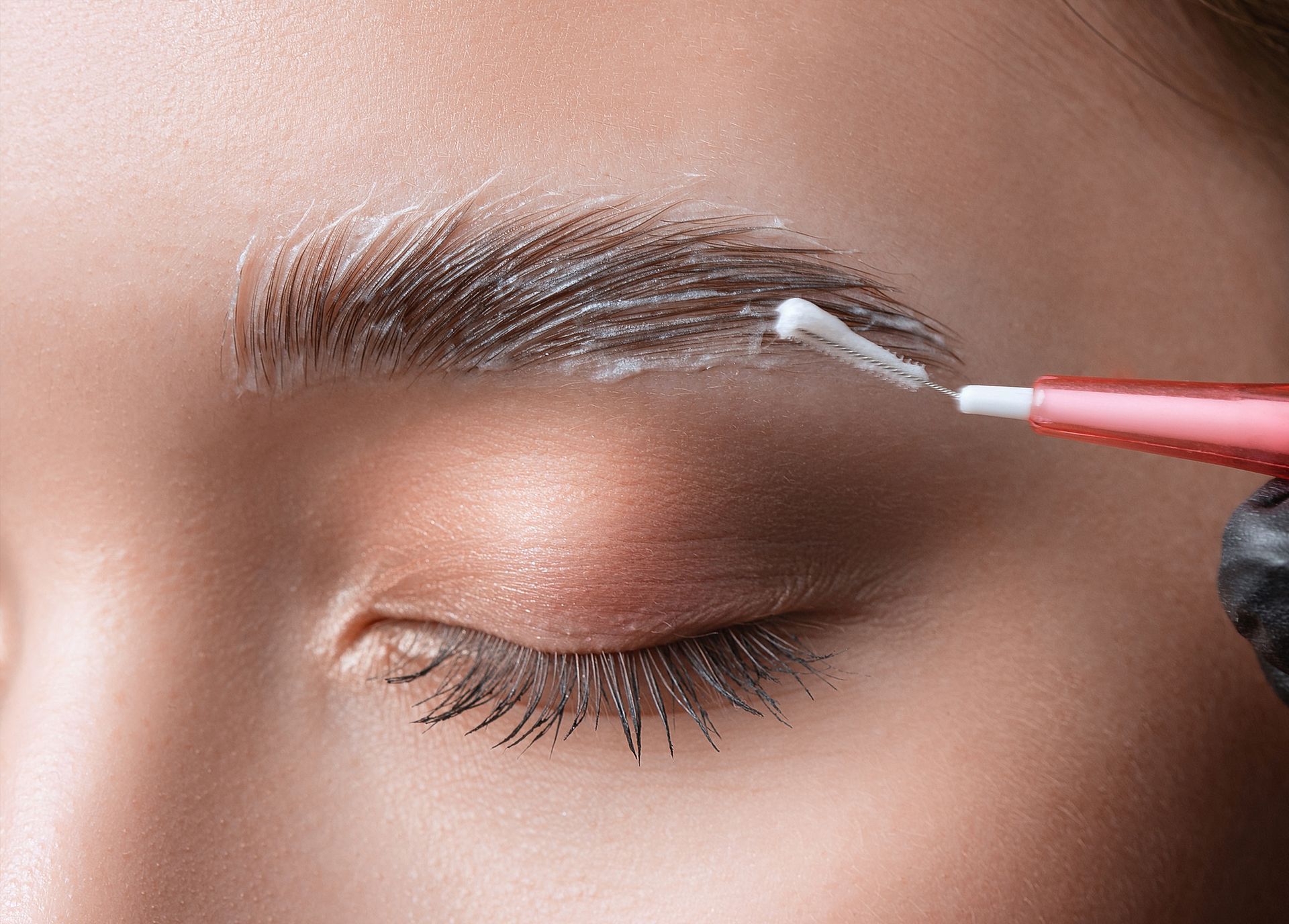 A woman is getting her eyebrows painted with a brush.