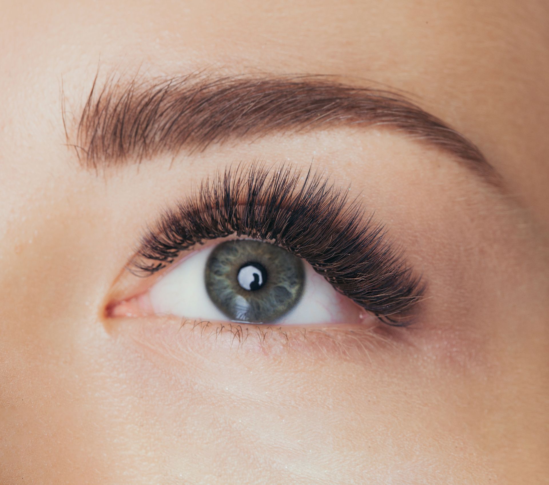 A close up of a woman 's green eye with long lashes.