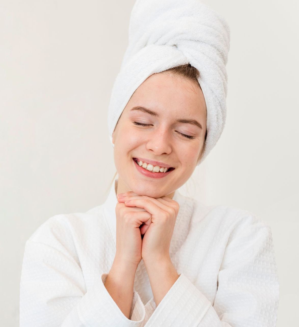 A woman with a towel wrapped around her head is smiling.