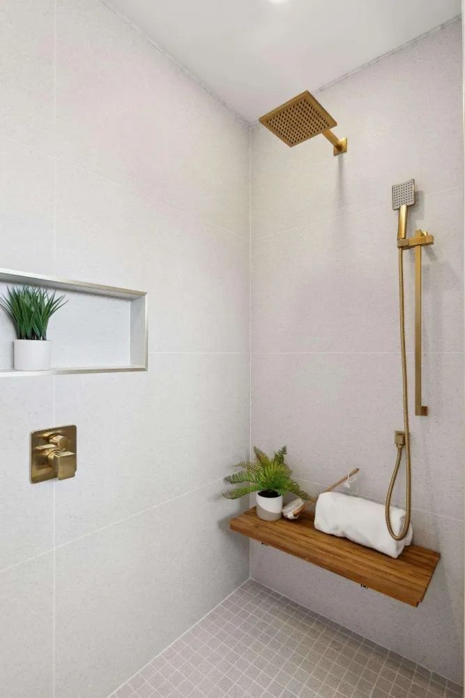 Modern shower with gold fixtures, a built-in bench, and a plant niche. White and gray color scheme.