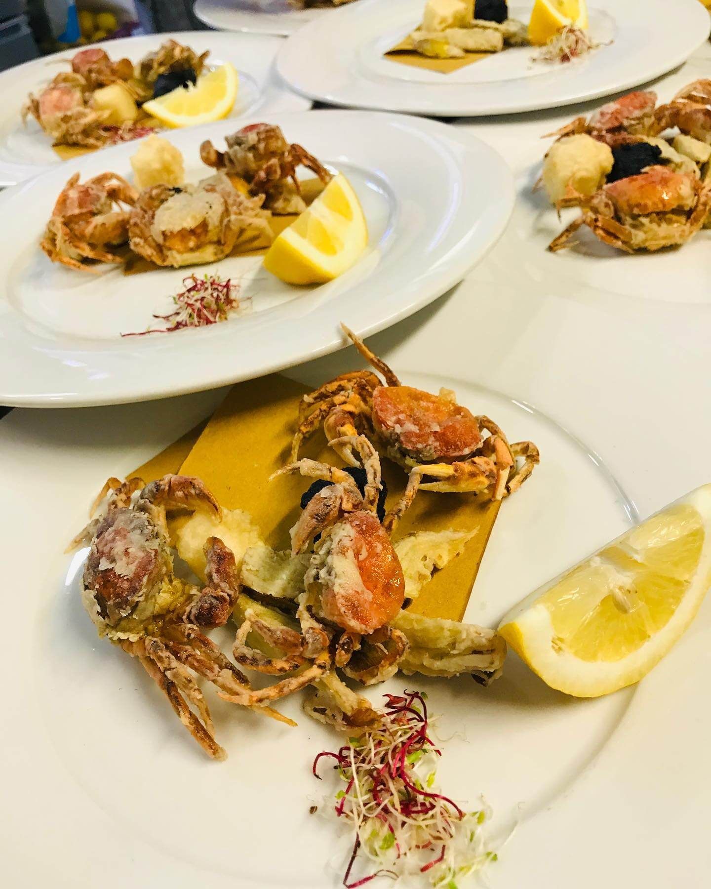 Un piatto bianco con sopra granchi fritti e fette di limone
