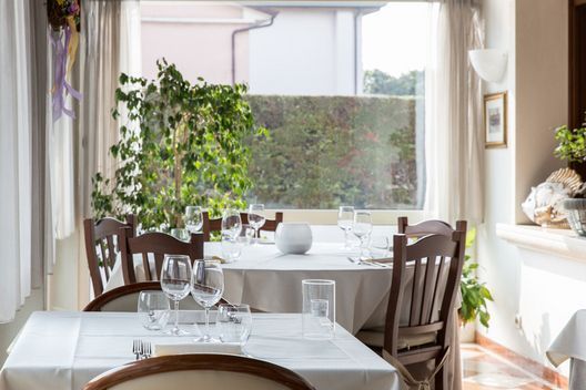 Una sala da pranzo con tavoli e sedie e una grande finestra.