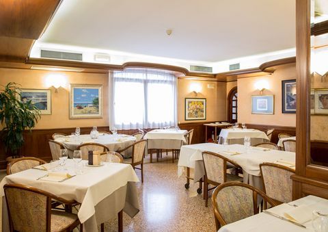 A large dining room with tables and chairs and paintings on the wall.