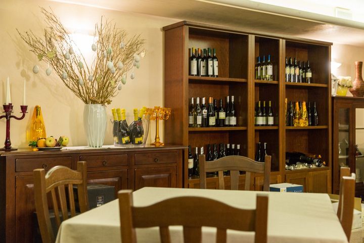 A dining room with a table and chairs and shelves full of wine bottles