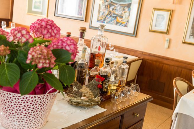 A table with a vase of flowers and bottles of liquor on it.