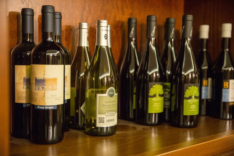 Bottles of wine are lined up on a wooden shelf.