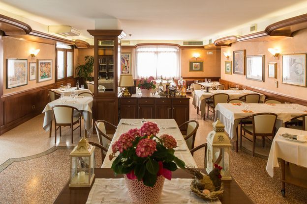 A restaurant with tables and chairs and a vase of flowers on the table