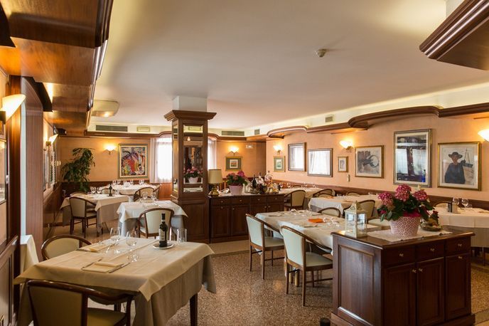 Una grande sala da pranzo con tavoli, sedie e quadri alle pareti.