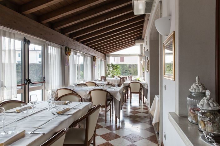 Un lungo corridoio con tavoli e sedie in un ristorante